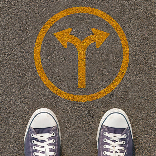 Pair of shoes standing on a road with traffic sign